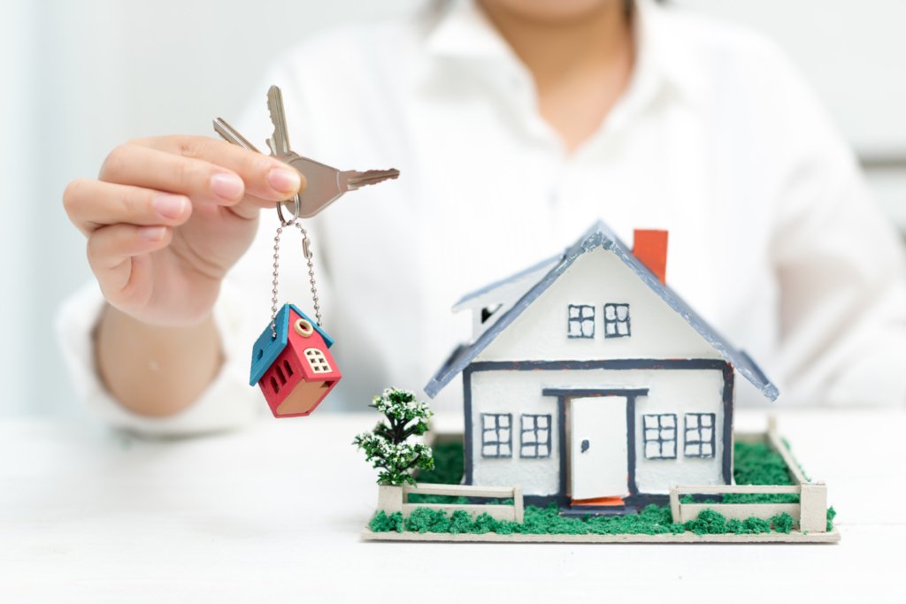 Key handover next to model house, symbolizing how to sell resale flat fast in today’s competitive real estate market.